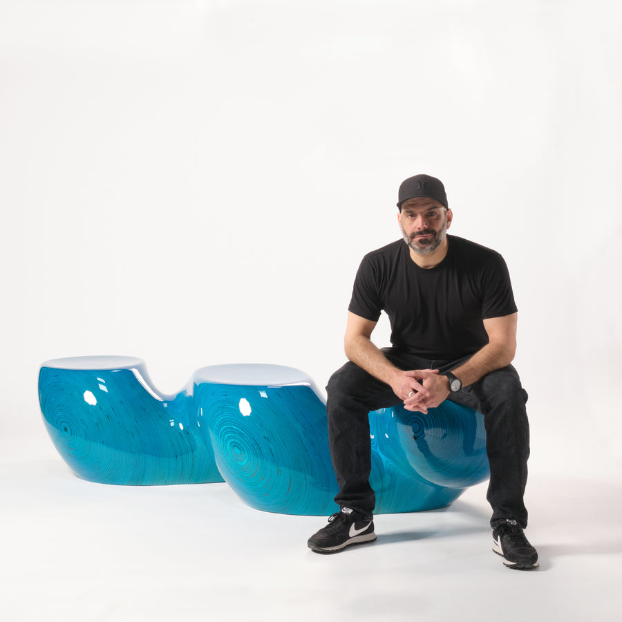 Ezra Ardolino sits on his sculptural birch plywood bench, overlaid in epoxy resin. Represented by Tuleste Factory, an art & design gallery in Chelsea, New York city.